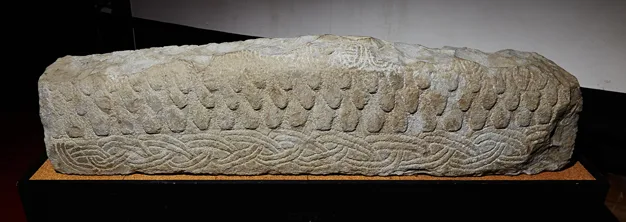 The Anglo-Norse hogback stone at St Bridget's, carved with a roof-shingle pattern along its curved ridge